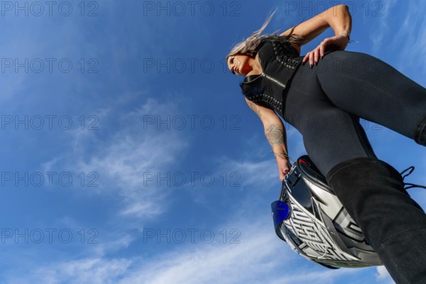 A stunning woman strikes a confident pose beside her high-performance motorcycle. With a fierce