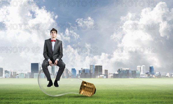 A businessman with glasses sits on a light bulb. concept of creativity in business