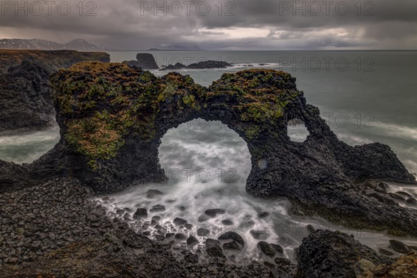 Rocky shore with a surf with foam on the water at Gatklettur