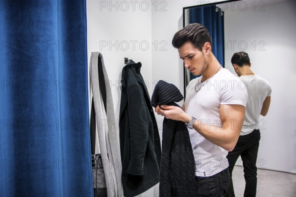 Young Handsome Man Trying on Clothes in Clothing Store', s Changing Room in Front of a Mirror or