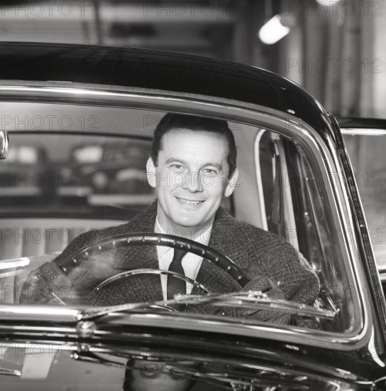 Driving in the 1960s. A man behind the steering wheel in his car looks happy. Sweden 1960.