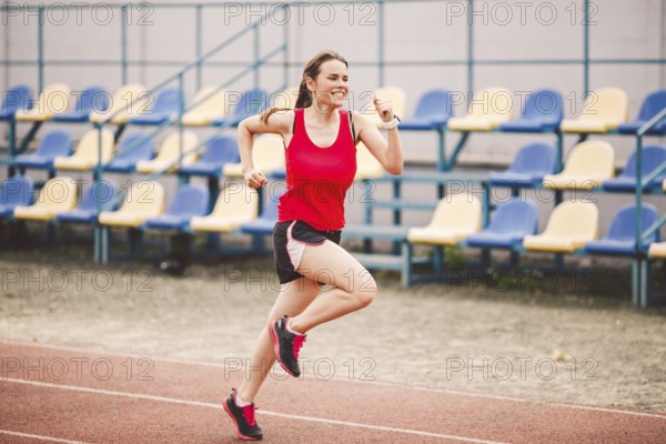Female runner jogging on stadium track, woman athlete running and working out outdoors, sport and