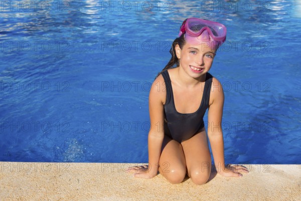 Blue eyes kid girl on knees on blue pool poolside with snorkel pink glasses