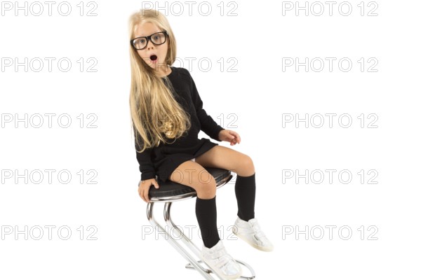 Isolated on white, pretty caucasian blonde little girl in black dress, glasses, black socks and