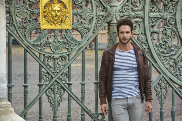 A man standing in front of a green gate in Piazza Castello in Turin, Italy, Europe