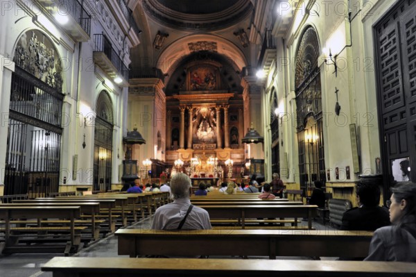 Madrid, Spain, Europe, Interior of a church with pews and an illuminated altar in the background,
