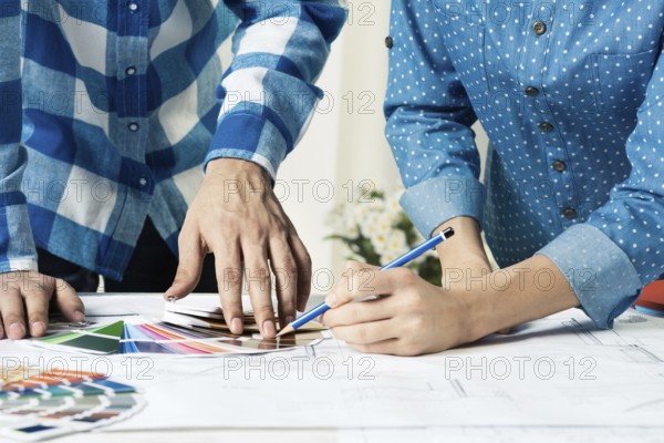Designers selecting color palette for design project. Human hands, technical drawing and color
