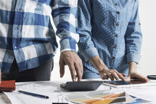 Designers working with color swatches and tablet computer at desk. Interior design, architectural