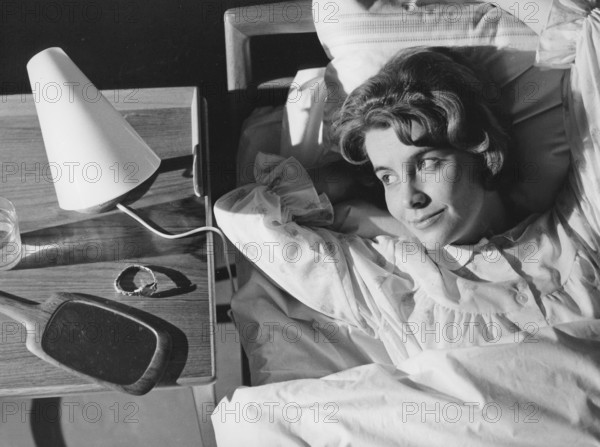 Sleep in the 1960s. A young woman lies comfortably ensconced in a bed. On the bedside table is a