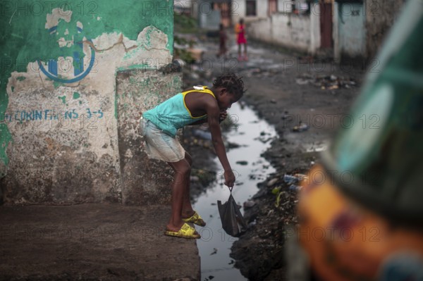 Child throwing rubbish into a gutter on the street, environmental pollution, poverty Kinshasa,