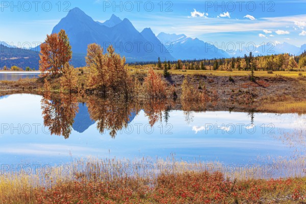 Smooth water of artificial lake Abraham reflects the Rocky Mountains. Sunny day in October.