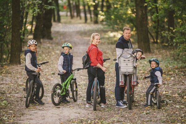 Parents and kids cycling on forest trail. family in warm clothes cycling autumn park. Family