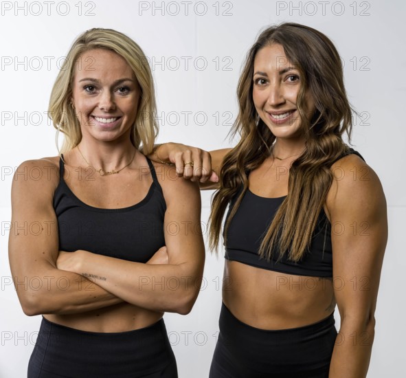 Two gorgeous athletic fit models pose confidently, their toned muscles highlighted by soft lighting