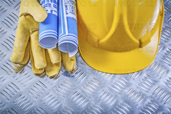 Blue engineering drawings hard hat safety gloves on corrugated metal background construction