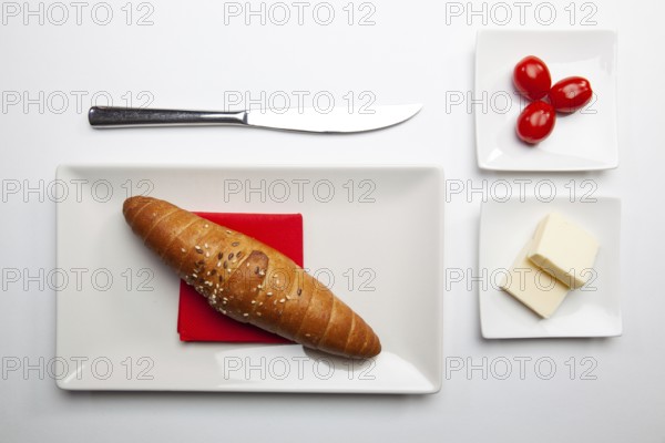Healthy breakfast. Block of fresh butter, french baguette and red cherry tomatoes on the white