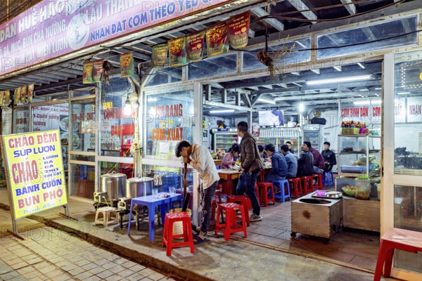 A street restaurant at night with diners at tables and vibrant neon lights, restaurant in the