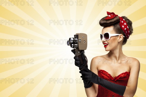 Vintage photo of glamorous pinup girl wearing a sexy red corset, shooting with an old retro cinema