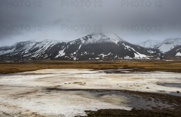 Icelandic landscape with frozen lake, mountains and meadow land covered in snow at snaefellsnes