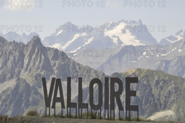 Name of Valloire write in metal letters, Valloire sign against a backdrop of majestic mountains and