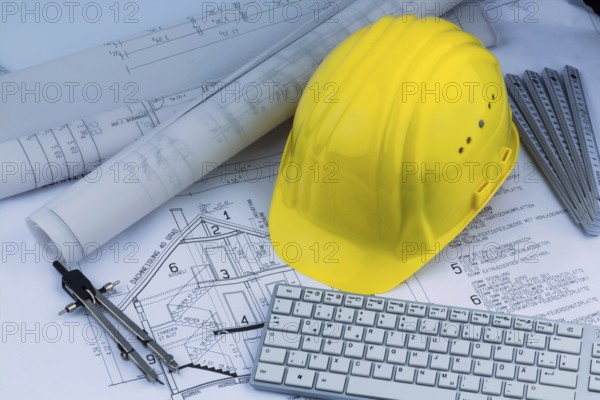 An architect's construction plan with a builder's helmet. Symbolic photo for financing and planning