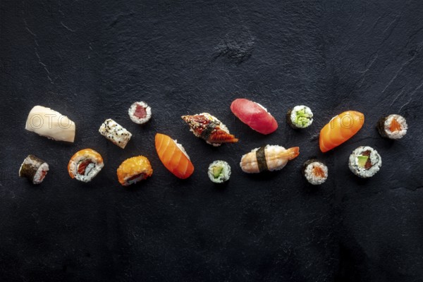Sushi overhead flat lay shot. Rolls, maki, nigiri on a black slate background, Japanese food.
