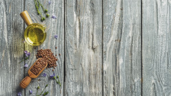 Flax seeds and flax oil. Brown linen seeds and flaxseed oil on old gray wooden background. Copy