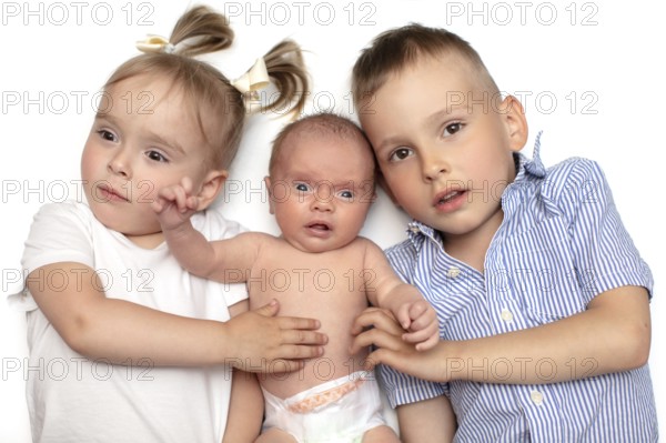 Brother and sister lying together with a newborn baby. Three small children of different ages.