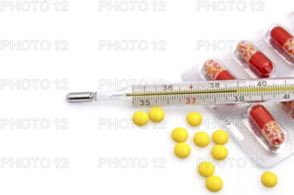 Thermometer with the yellow pills in bulk and red-white capsules in a package on a white