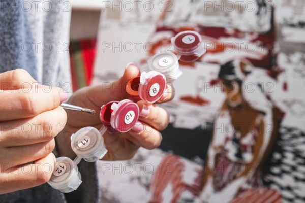 Female hands coloring canvas Picture by numbers car and girl. Creative hobby. Painting for