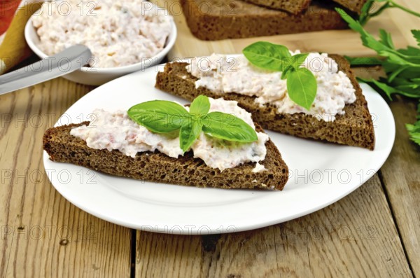 Sandwiches on two pieces of rye bread with cream of salmon and mayonnaise, basil, knife, napkin on