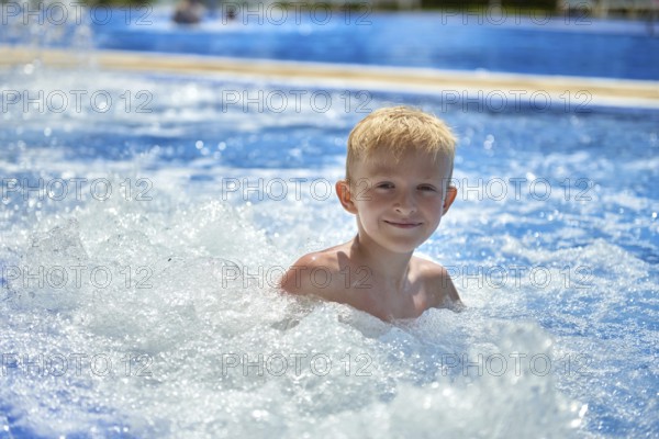 Young boy kid child eight years old splashing in swimming pool having fun leisure activity. Boy