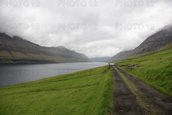 Gravel street on the Faroe Islands with the village Hvannasund in the background, Hvannasund, Faroe