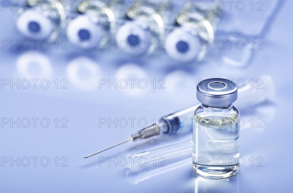 Single use syringe for injection treatment on medical table with vials of liquid drug doses flu