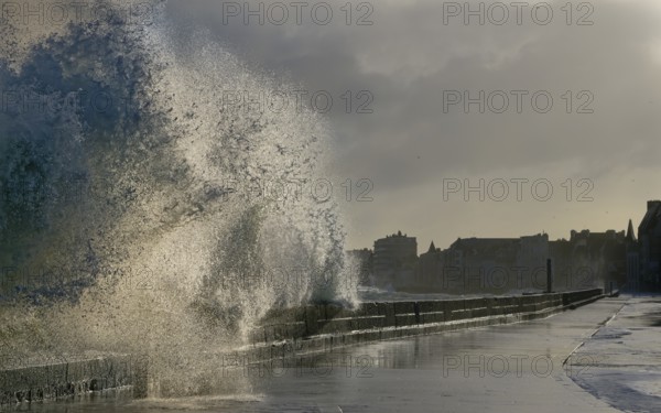 Massive ocean splash against a sea wall on a stormy, overcast day by the coast, Saint-Malo,