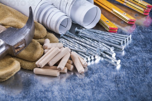 Construction drawings hammer safety gloves wooden meter metal nails and dowels on scratched