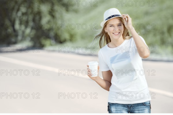 Beautiful young woman walking with a disposable coffee cup, drinking coffee and smiling against the