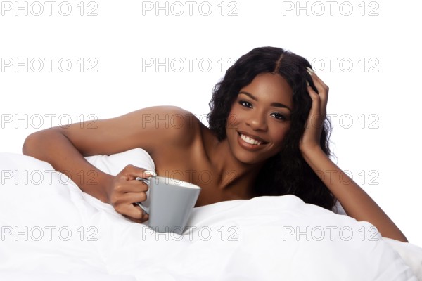 Beautiful happy smiling african woman in white bed waking up with coffee or tea after a deep sleep,