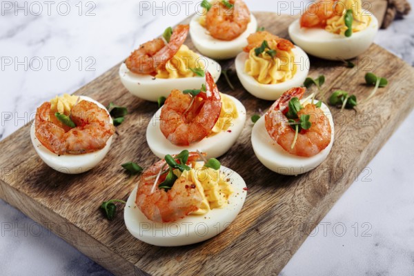 Boiled eggs stuffed with yolk and seasoned with mayonnaise, stuffed eggs with shrimp, on a wooden