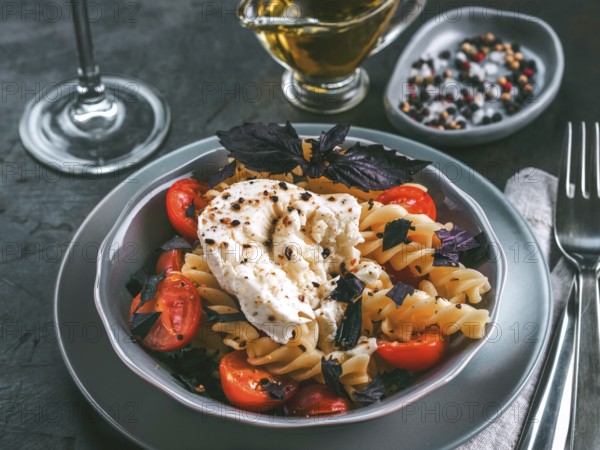 Tasty italian fusilli pasta with cherry, mozarella or buratta cheese and fresh basil. Dish with