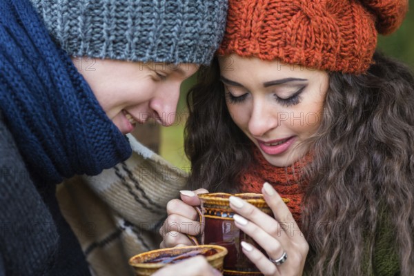 Young couple in love with a cup of coffee in the autumn garden