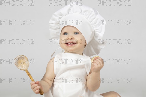 Child cooking. Beautiful little girl in cooking clothes with a big spoon. The child is one year old