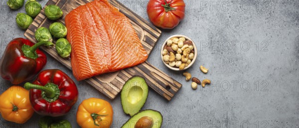 Fresh raw salmon fillet on wooden cutting board, organic bio vegetables and nuts on rustic stone