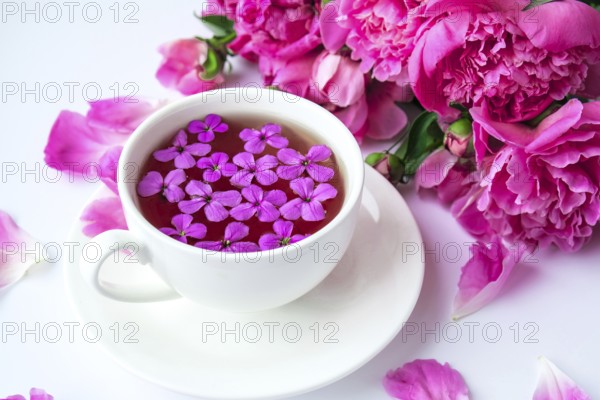 Creative layout with pink peonies flowers and cup of tea on bright table. Spring Seasonal