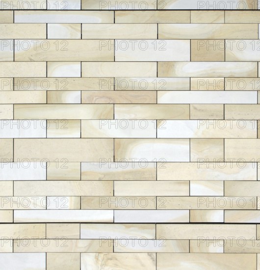 Full frame image of a wall made of large flat blocks of textured yellow light brown york stone in