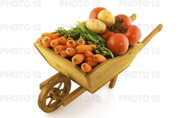 Wooden wheelbarrow full with fresh vegetables isolated over white