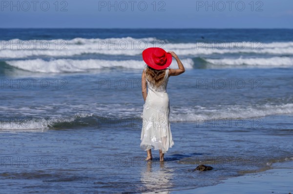 Breathtaking woman basks in beach bliss, near a pier, under clear blue skies, embracing the