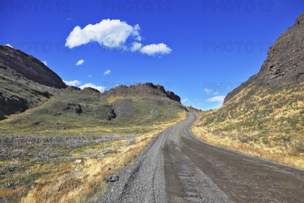 Beautifully curved gravel road between the hills. The National Park Torres del Paine. Chilean