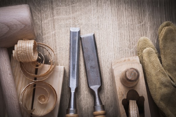 Wooden bricks mallet curled up shavings planer firmer chisels leather gloves on wood background