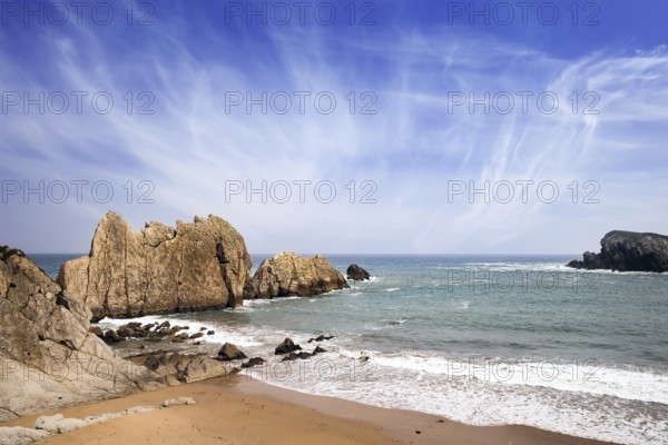 Snow-white sea foam glistens in the dim autumn sun. Cantabria, Spain. Playa de la Arnia beach.