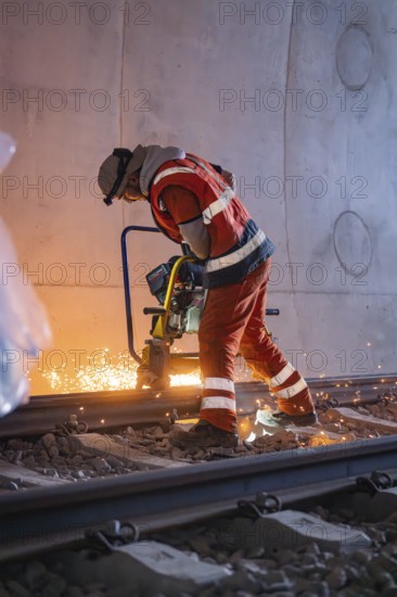A worker grinding rails in a tunnel, sparks spraying, rail welding, track construction Hermann